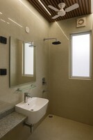 Un baño moderno con tocador, espejo, ducha y ventilador de techo.