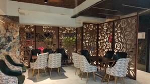 A modern indoor seating area with patterned chairs and a ceiling fan. - Inn Of Joy (Noida)