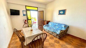 Una habitación con una mesa de comedor, sillas, un sofá, un televisor y un extintor.