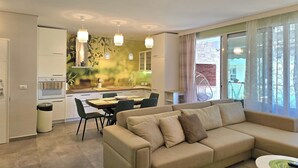 Un appartement moderne comprenant un salon, un coin repas et une cuisine. On y trouve un canapé beige, une table à manger avec des chaises, et une cuisine avec des meubles blancs.