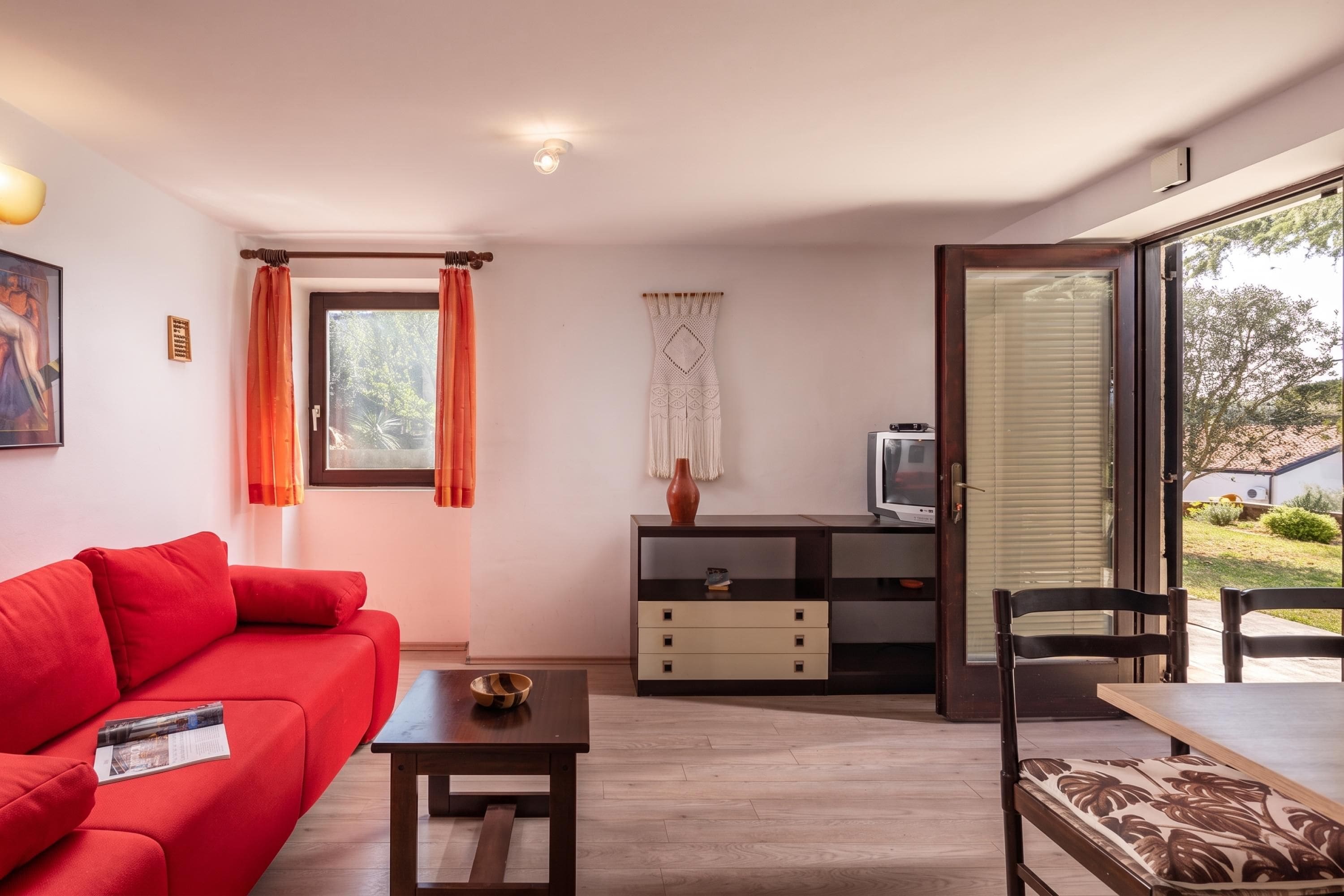 A modern living room with a red sofa, a wooden coffee table, and a TV on a wooden cabinet.