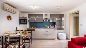A modern kitchen with a central island, built-in appliances, and a dining area with a red sofa.
