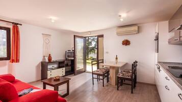 A compact living space with a kitchenette, a dining area, and a seating area with a red sofa.