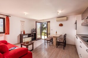 A compact living space with a kitchenette, a dining area, and a seating area with a red sofa. - The Wave - Apt With Seaview and Garden (Kostrena)