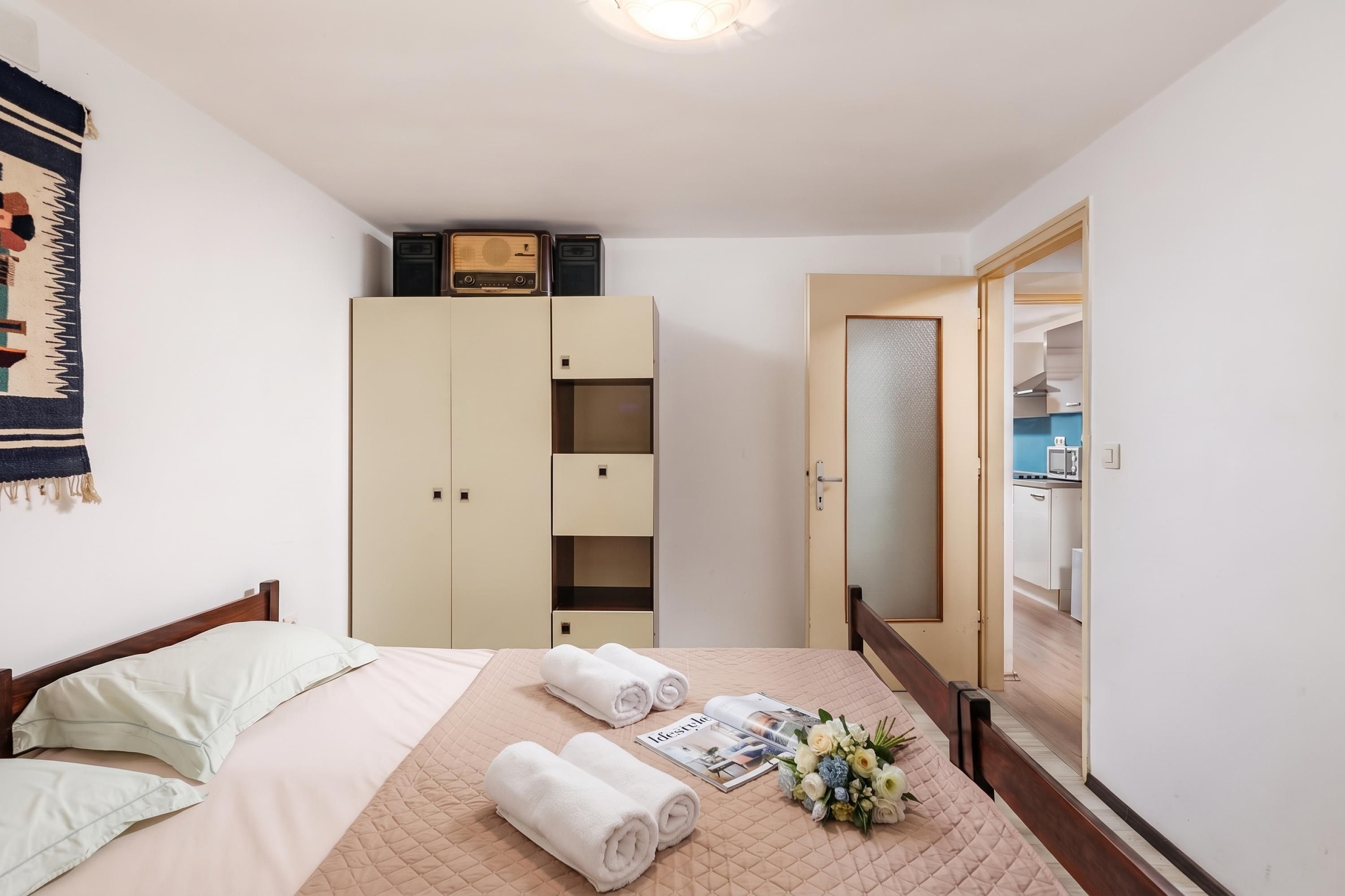 Habitación de hotel con cama, armario, radio y vistas a la cocina.