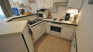 A compact kitchen with white cabinets, a microwave, a coffee maker, and a stove. - Apartment in Duinbergen With Side Sea View (Knokke-Heist)