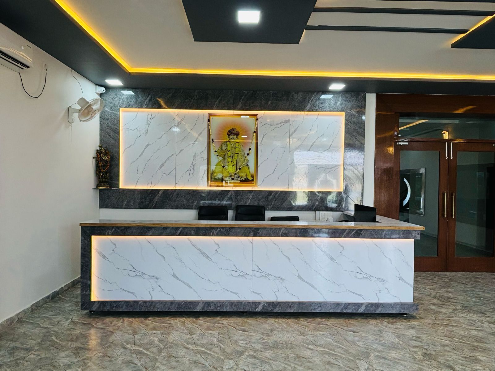A reception desk with marble countertops and a framed artwork above it.