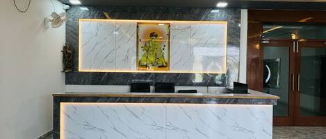 A reception desk with marble countertops and a framed artwork above it.