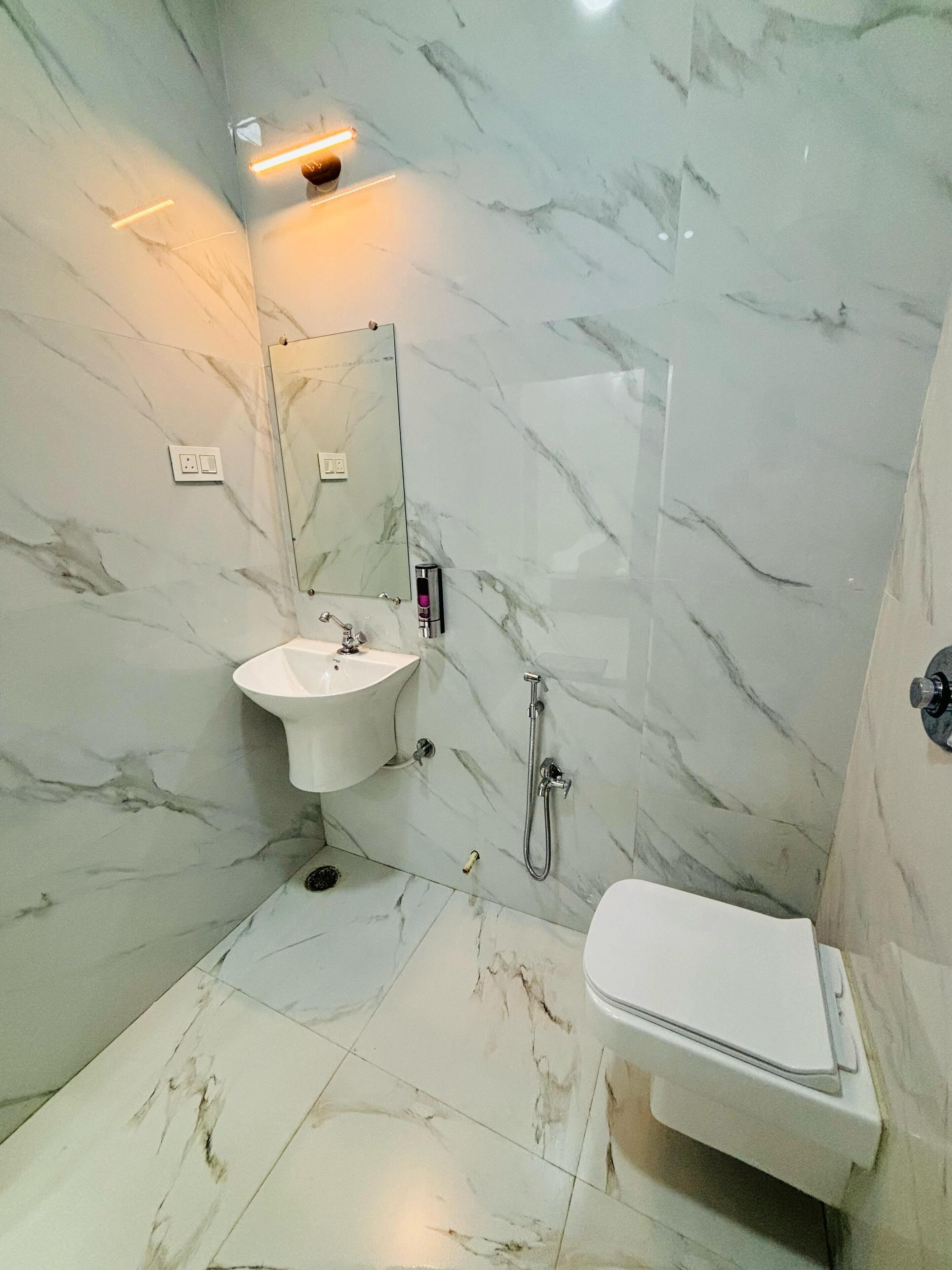 Un bagno con lavabo in marmo, uno specchio, una doccia e un water.
