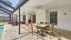 A covered patio with a dining table and chairs, a ceiling fan, and a pool in the background. - Private Pool & Patio: Niceville Family Home (Niceville)