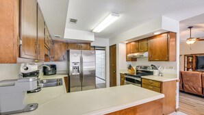 A modern kitchen with stainless steel appliances, wooden cabinets, and a central island. - Private Pool & Patio: Niceville Family Home (Niceville)