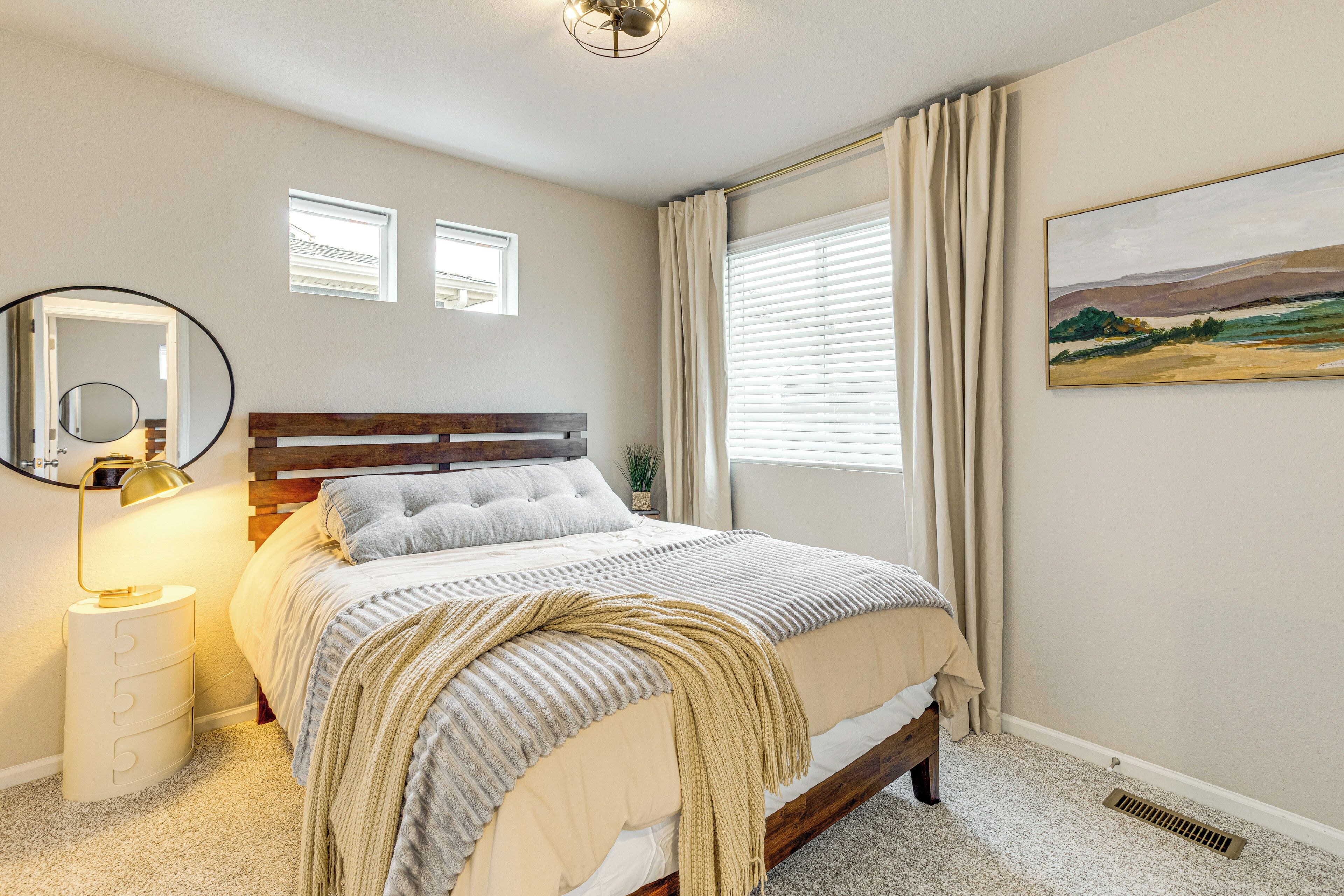 Een slaapkamer met een bed, een bedlampje en een raam met gordijnen.