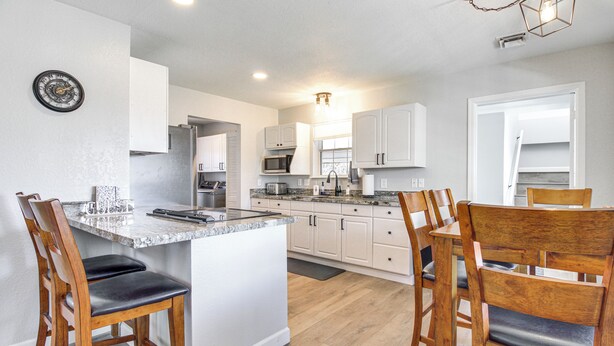 A modern kitchen with white cabinets, a granite countertop, and wooden chairs. - Walk to Dtwn Show Low: Townhome w/ Balcony (Show Low)