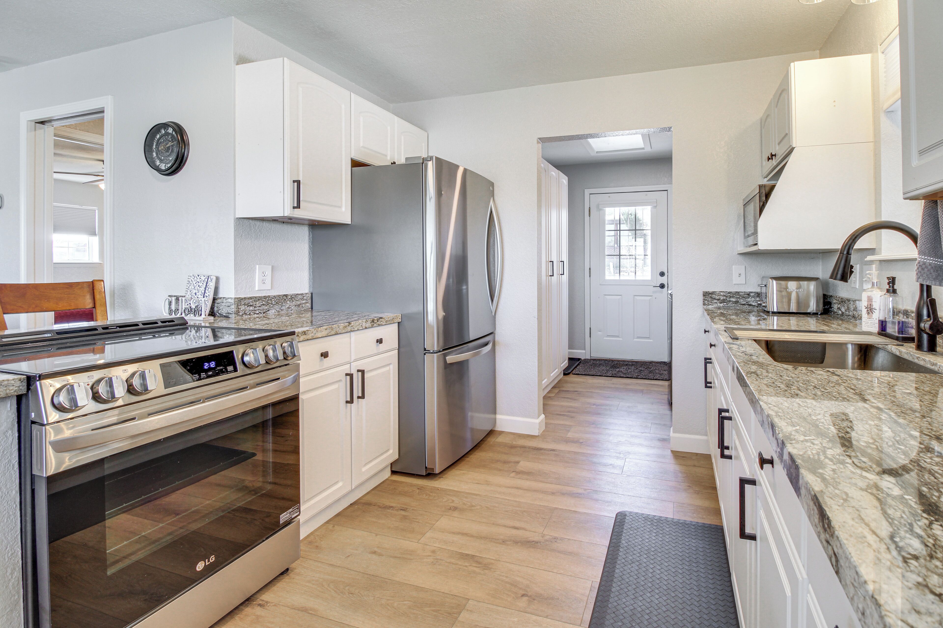 A modern kitchen with stainless steel appliances, white cabinetry, and a granite countertop.