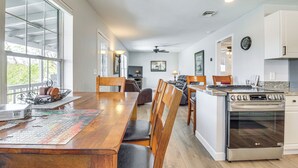 A spacious kitchen with a wooden dining table, chairs, a large island with an oven, and a television. - Walk to Dtwn Show Low: Townhome w/ Balcony (Show Low)