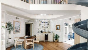 Een moderne keuken met witte kasten, een centraal eiland en een eetgedeelte met een ronde tafel en stoelen.