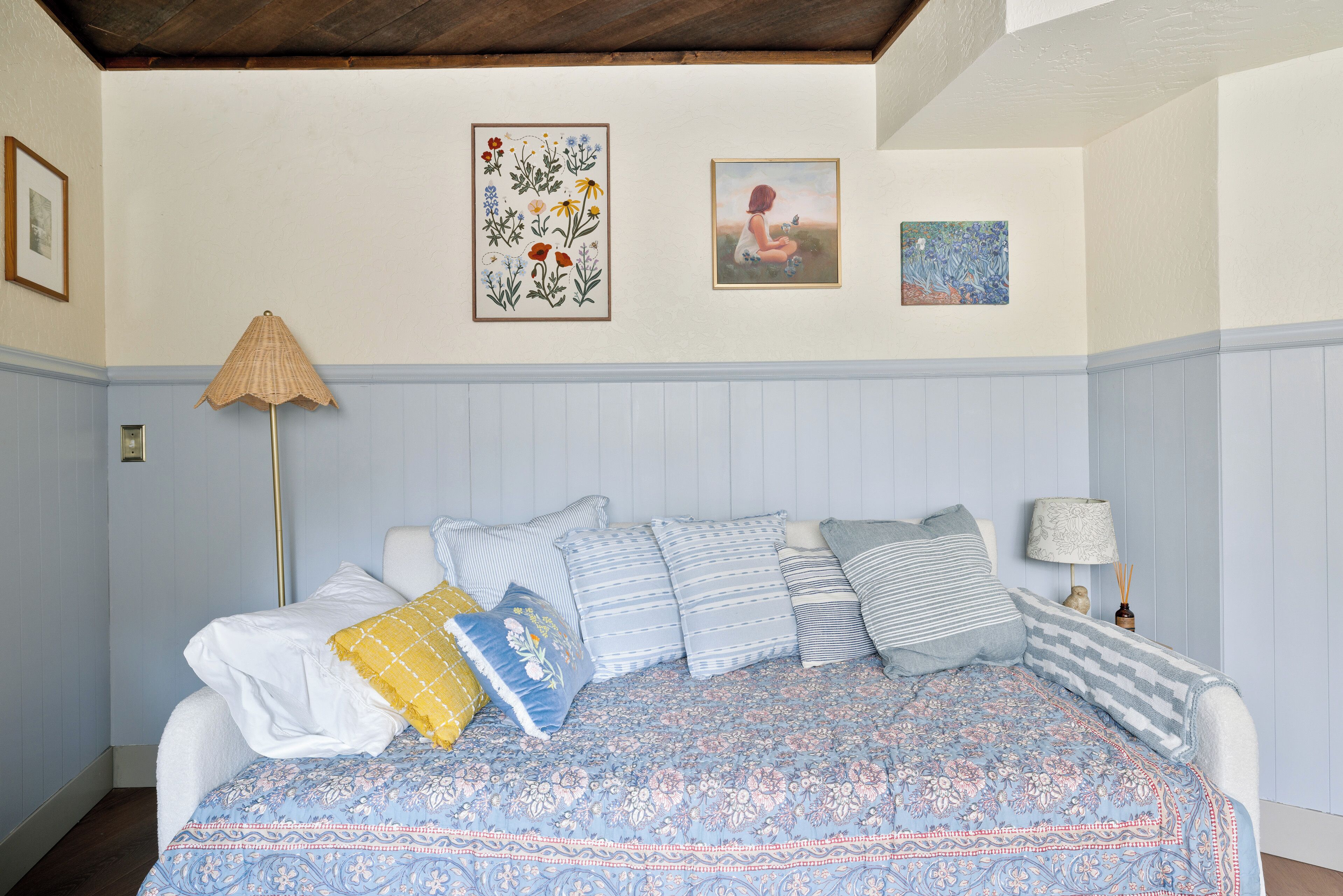 A bedroom with a bed, pillows, a lamp, and wall art.