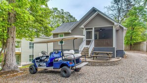 Une maison avec une véranda, une table de patio et un véhicule de golf garé devant.