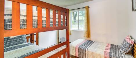 A room with two bunk beds, a window with curtains, and a ceiling light.