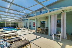 A covered outdoor area with a pool, lounge chairs, and a table with chairs. - Community & Private Pools: Davenport Golf Getaway! (Davenport)