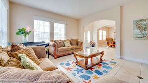 A spacious living room with a sofa, a coffee table, and a dining area in the background. - Spacious Group Getaway! Pool, Patio + Game Room (Davenport)