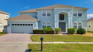 A two-story house with a garage, a front entrance with a door, and a driveway leading to the garage. - Spacious Group Getaway! Pool, Patio + Game Room (Davenport)