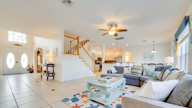 A spacious living room with a staircase, a ceiling fan, and a large window. - Spacious Group Getaway! Pool, Patio + Game Room (Davenport)