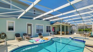 A covered swimming pool with lounge chairs and a small building with a door. - Spacious Group Getaway! Pool, Patio + Game Room (Davenport)