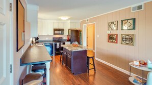 Una cocina moderna con una isla central, armarios blancos y suelo de madera.