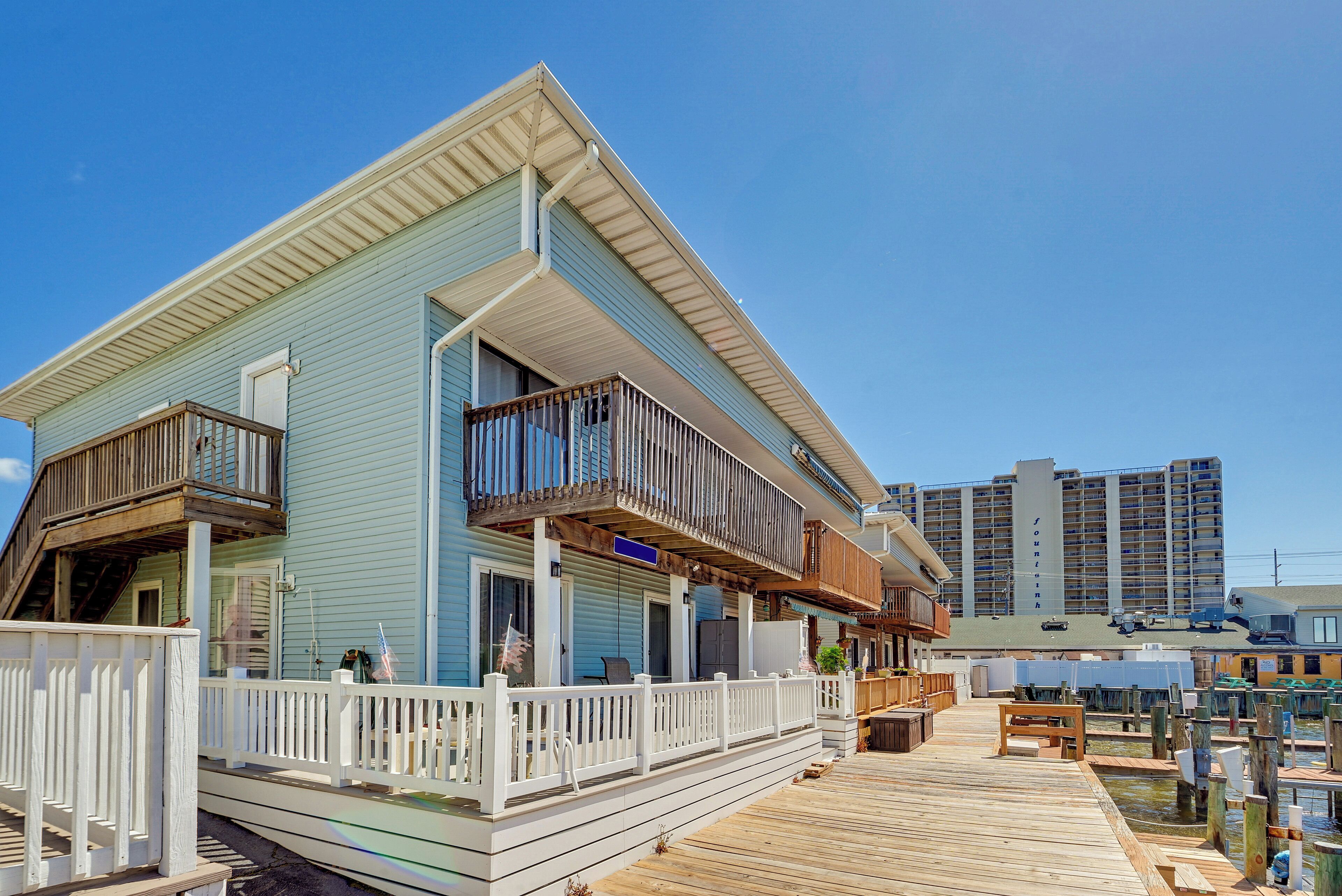 A coastal building with a wooden deck, balconies, and a view of the marina.