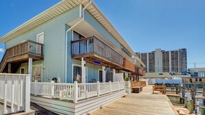 Un edificio frente al mar con terraza de madera, balcones y vista al puerto deportivo.