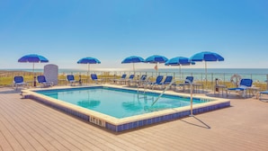 A pool area with blue umbrellas, lounge chairs, and a view of the ocean. - Sunset-view Resort Condo on Perdido Key (Pensacola)