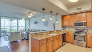 A modern kitchen with wooden cabinets, stainless steel appliances, and a large island. - Sunset-view Resort Condo on Perdido Key (Pensacola)