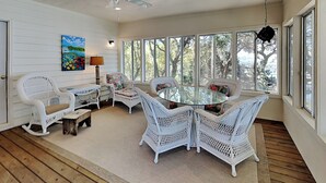 A sunlit room with wicker furniture, large windows, and a ceiling fan. - The Pack House | Waterfront Home, Private Dock (Topsail Beach)