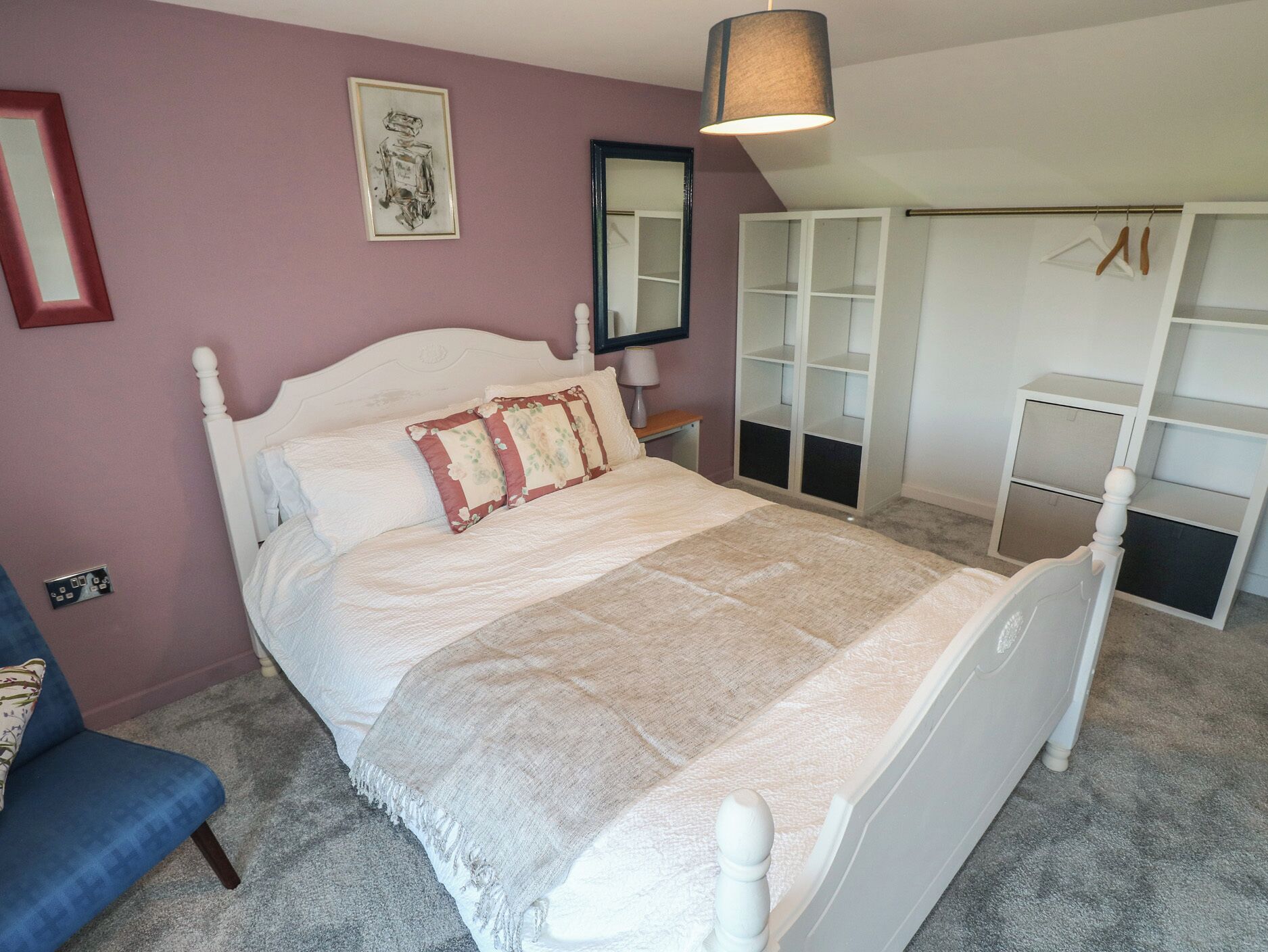 Un dormitorio con cama, armario, espejo y lámpara colgante.