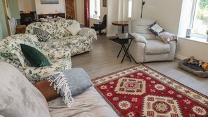 A living room with a sofa, armchair, and a patterned rug. - Chapel Hill House (Pembroke)