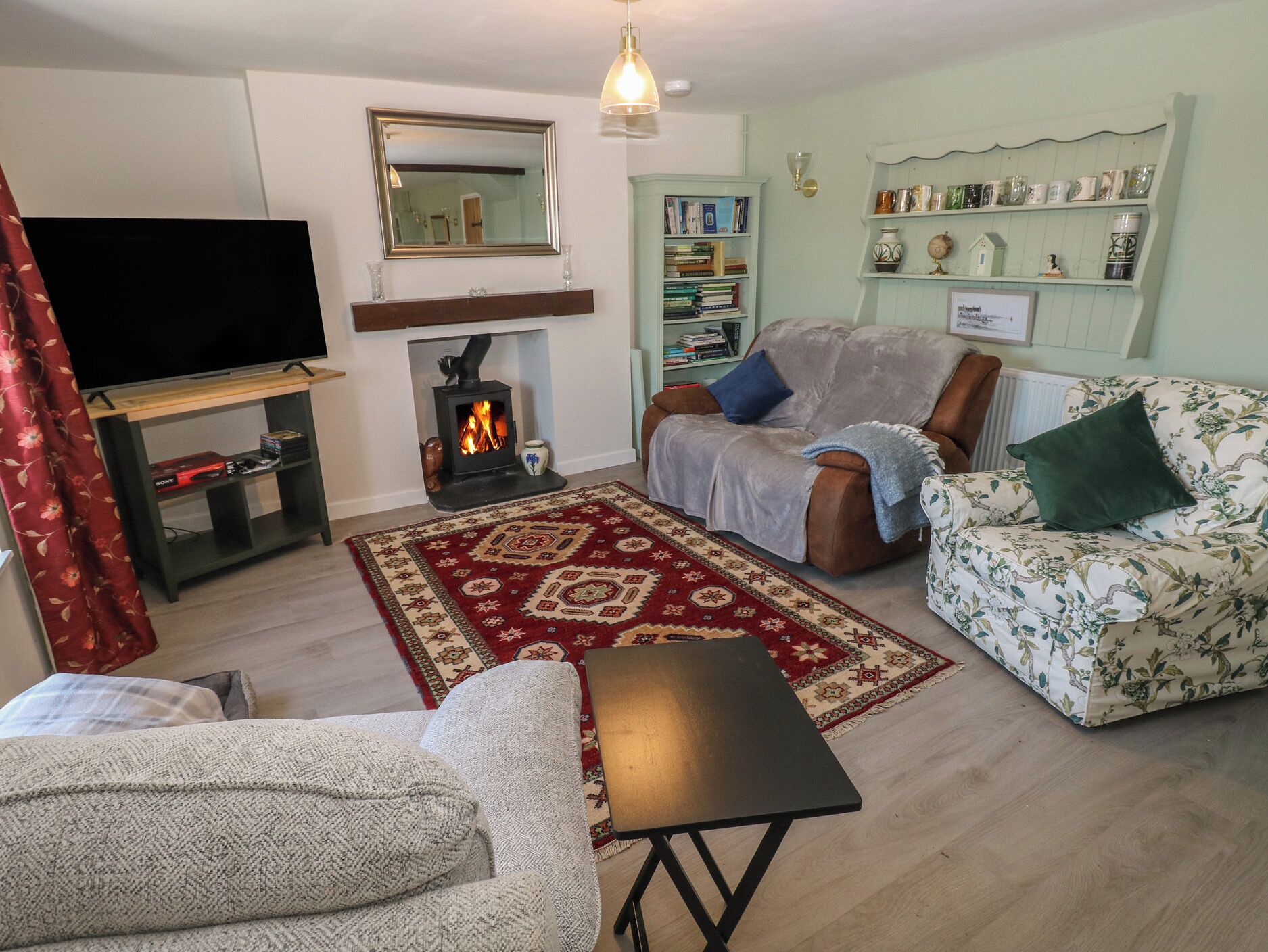 Una sala de estar con chimenea, sofá, sillón y televisión.