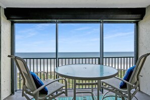 A balcony with a glass table and chairs, overlooking a beach. - Oceanfront Pool Beach Gear Tennis Smart TVs (St. Augustine)