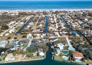 Vista aérea de una zona residencial con casas, un río y una playa al fondo.