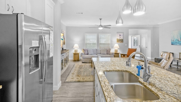 A modern kitchen with a stainless steel refrigerator, granite countertops, and a double sink.