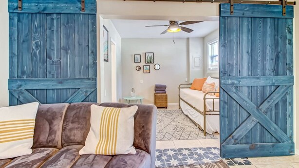 A room with a sofa, a bed, and a large blue wooden door. - Free Parking Smart TV Uptown St Augustine (St. Augustine)