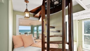 Un dormitorio con vista al océano, una escalera de madera y un balcón con vistas.