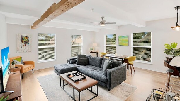 Un salon moderne avec un canapé d’angle, une table basse et un coin repas agrémenté d’une chaise jaune.