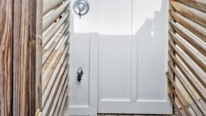 A white door with a metal handle and a peephole, flanked by wooden slats.