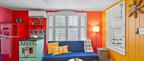 A compact living space with a red refrigerator, a blue sofa, and a kitchenette with a green stove.