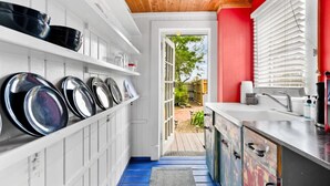 Una cocina estrecha con armarios blancos, una pared de acento roja y vistas a un patio trasero.