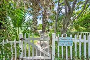 A gated pathway leading to a building with a sign reading "Please Close The Gate." - Heated Pool Tiki Lounge Steps to Beach Games (St. Augustine)