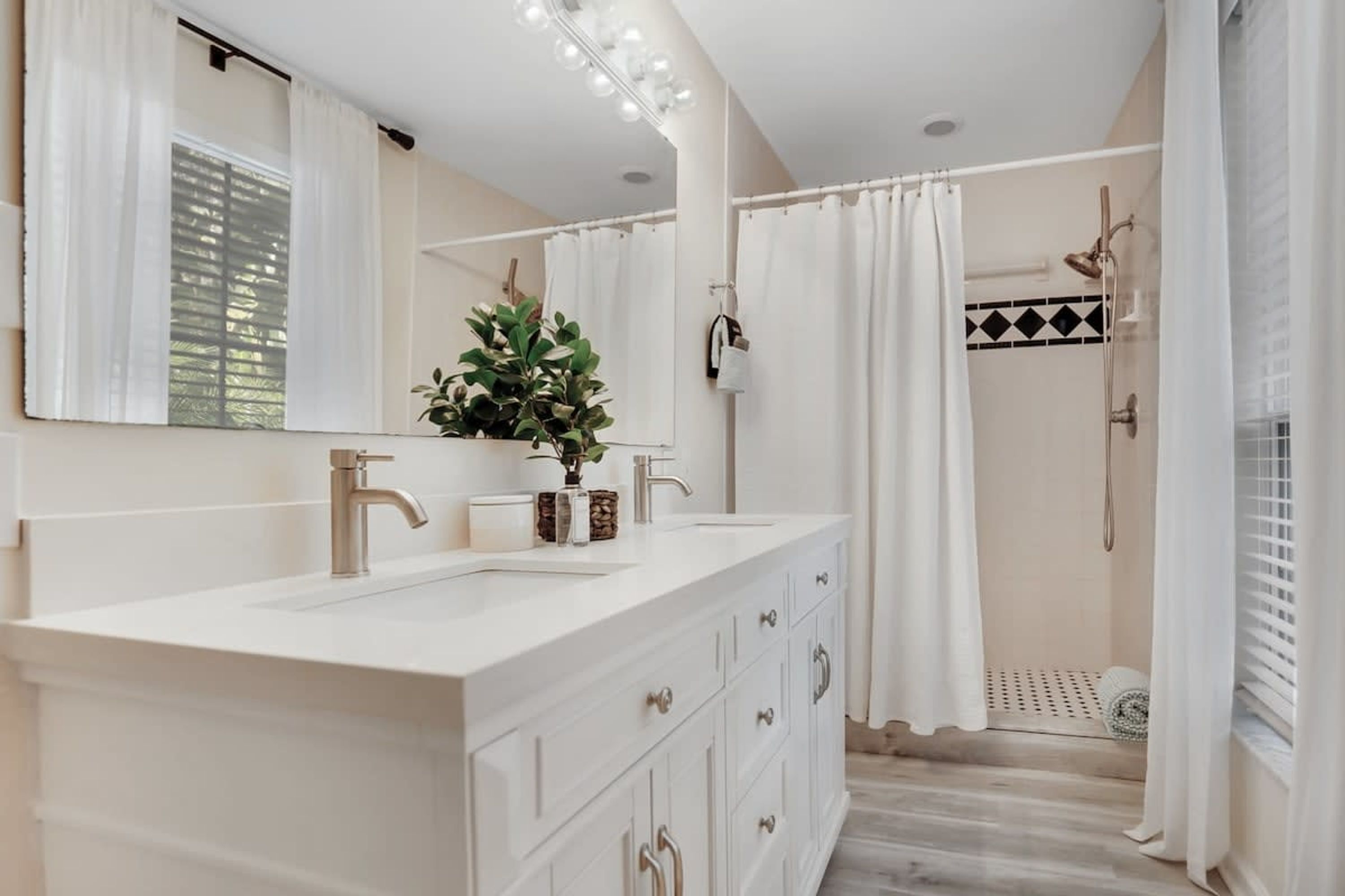 A bathroom with a white vanity, a large mirror, and a shower area.