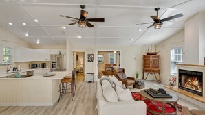 Uma sala de estar espaçosa com lareira, uma área de jantar e uma cozinha equipada com eletrodomésticos modernos.