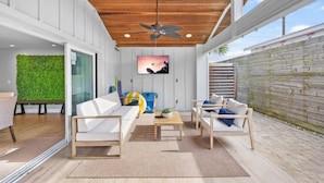 Un espace de vie extérieur moderne, doté d’un plafond en bois, de murs blancs et d’un mur végétal.